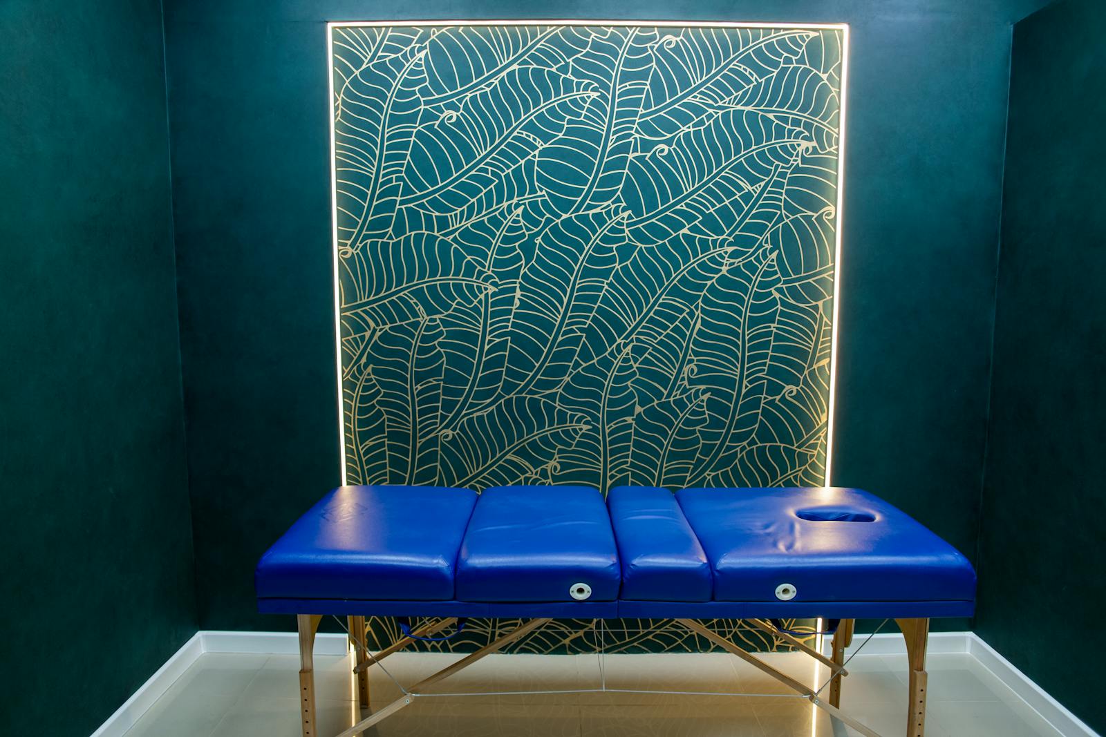 Treatment room with a softly lit botanical wall panel