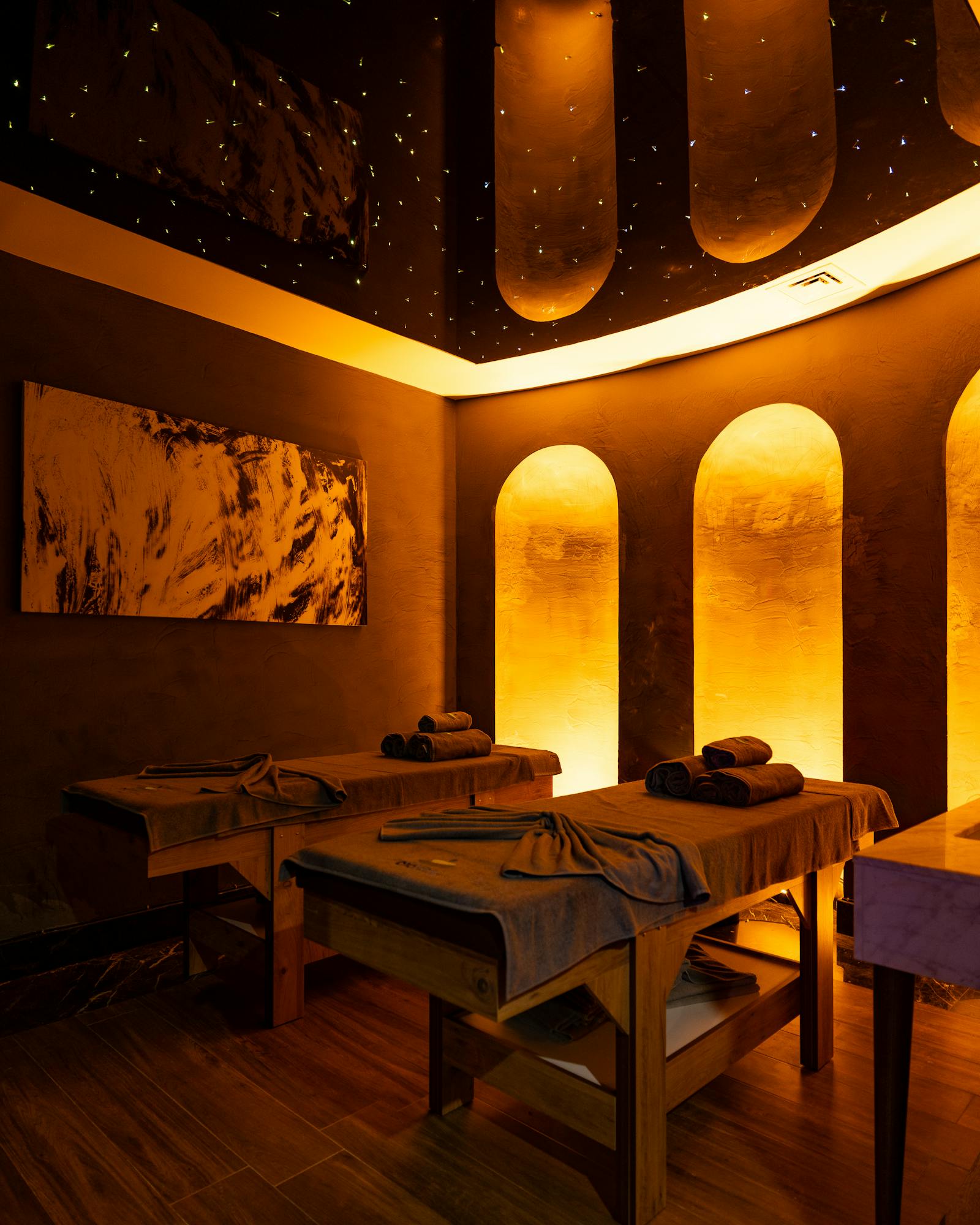 Warm-lit treatment space with arched alcoves and folded towels